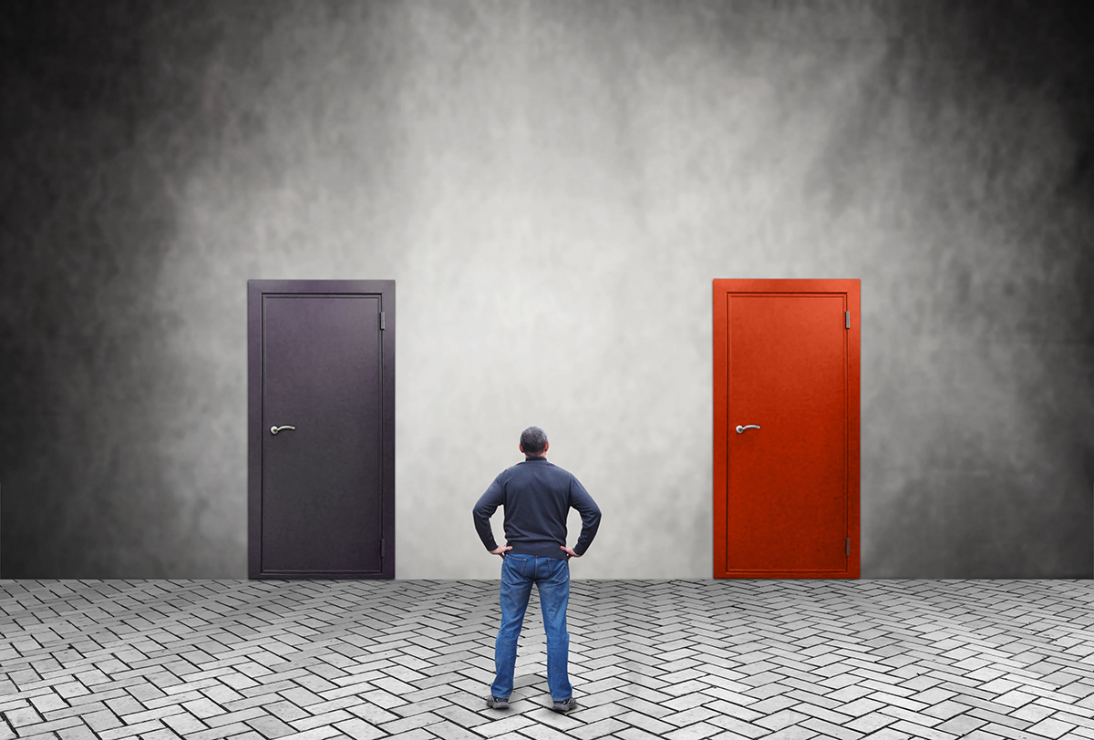 Man with hands on hips looking at a gray door and a red door